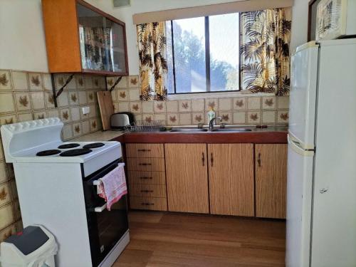 uma cozinha com um fogão branco e um lavatório em Surfside two-bedroom holiday upstairs em Batemans Bay