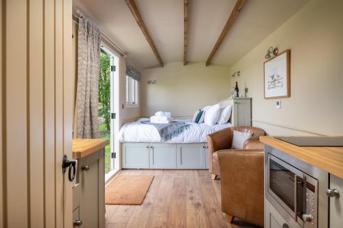 1 dormitorio pequeño con 1 cama y 1 sofá en Great Ashley Farm Bed and Breakfast & Shepherds Huts en Bradford on Avon