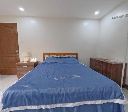 um quarto com uma cama azul e uma cómoda de madeira em Studio Room Casa Loreto near Ayala Center Cebu em Cebu