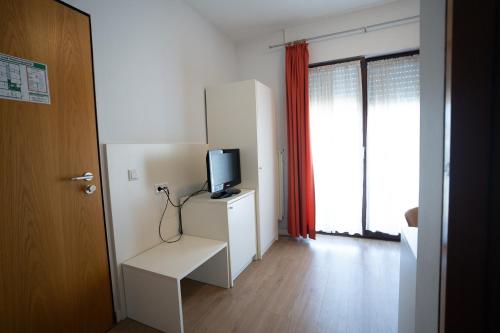 Ein weißes Zimmer mit einem TV auf einem weißen Schrank. in der Unterkunft AP Hotel Viernheim Mannheim am Kapellenberg in Viernheim