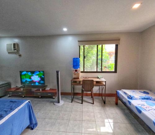 um quarto com 2 camas, uma secretária e uma televisão em Studio Room Casa Loreto near Ayala Center Cebu em Cebu