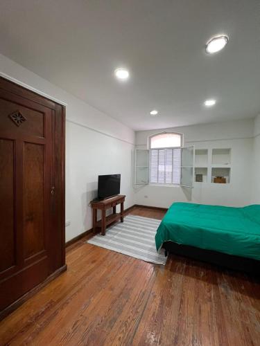 Schlafzimmer mit einem grünen Bett und Holzboden in der Unterkunft CASA MORENO se paga en USD o Dolar Blue! No se confunda in Buenos Aires