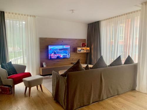 a living room with a couch and a flat screen tv at Luxury Mountain Hotel Apartment in Andermatt