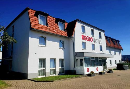 a white building with a red roof at REGIOHOTEL Salzland Schönebeck 