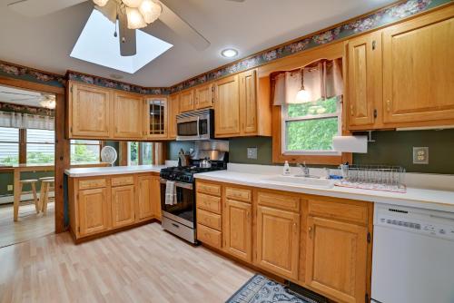 a kitchen with wooden cabinets and white counter tops at Cayuga Lake Retreat in Seneca Falls with Dock! in Seneca Falls