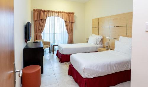a hotel room with two beds and a television at Al Raya Hotel Apartments in Dubai