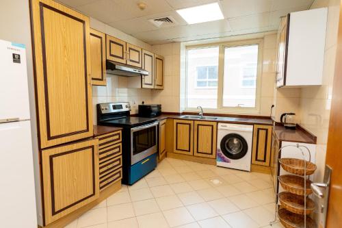 cocina con armarios de madera, lavadora y secadora en Al Raya Hotel Apartments, en Dubái