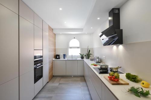 a kitchen with white cabinets and fruits and vegetables on a counter at Duplex Los Tinos II 32 by VillaGranCanaria in Maspalomas
