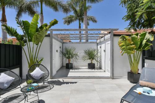un patio con palmeras, sillas y plantas en Duplex Los Tinos II 32 by VillaGranCanaria, en Maspalomas