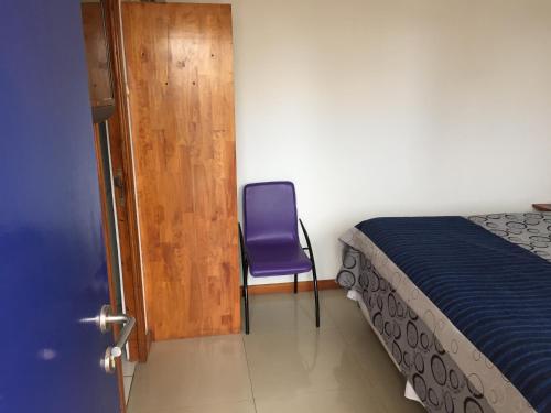 a bedroom with a purple chair next to a bed at Hotel Esmeralda in Iquique