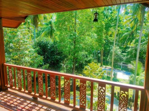 a balcony with a large window looking out at the forest at Family Resort in Baan Tai