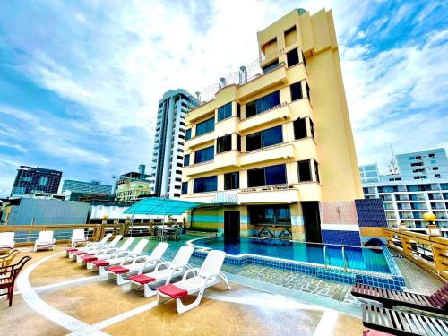 a hotel with a pool and chairs and a building at AA Hotel Pattaya in Pattaya