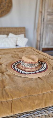 un chapeau en paille assis au-dessus d'un lit dans l'établissement Lodge Luxe et insolite spirit of Bali - La Noccemada, à Saint-Julien