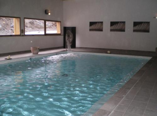 a swimming pool with blue water in a room with windows at Orelle 3 Vallées - Studio 4 personnes in Orelle