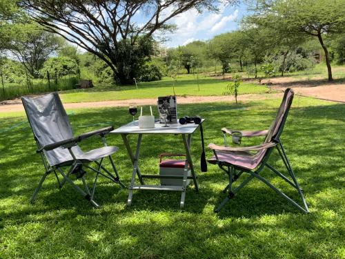 two chairs and a table in the grass at Lorato Lodge and Camping in Muchenje