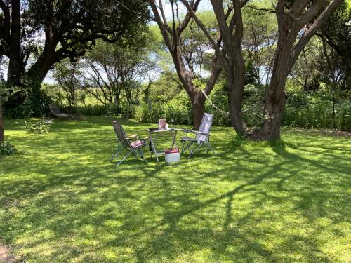 two chairs and a table in the shade of a tree at Lorato Camping in Muchenje