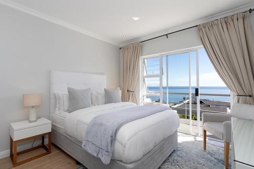 a white bedroom with a bed and a large window at Stunning Sea View Apartment - Camps Bay in Cape Town