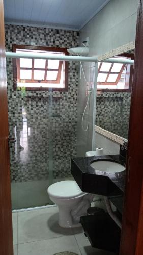 La salle de bains est pourvue de toilettes, d'un lavabo et d'un miroir. dans l'établissement Apto Duplex Condomínio Maranduba Ville II Sapê a 100 mts da praia, à Ubatuba