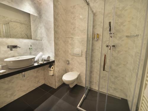 a bathroom with a shower and a toilet and a sink at Ramada Airport Hotel Prague in Prague