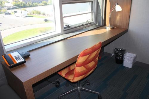 a wooden desk with a chair and a window at Aloft Syracuse Inner Harbor in Syracuse