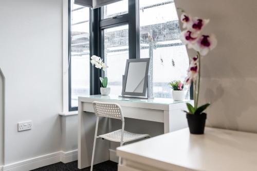 a desk in a room with a mirror and flowers at K Suites - Colne House in Lowestoft
