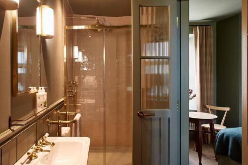 a bathroom with a shower with a sink and a mirror at Dusk at The Sun Inn Felmersham in Sharnbrook