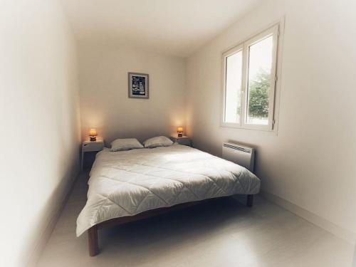 ein Schlafzimmer mit einem Bett in einem Zimmer mit einem Fenster in der Unterkunft Maison Mimosa avec jardin clos - plage à 500m in Chaucre