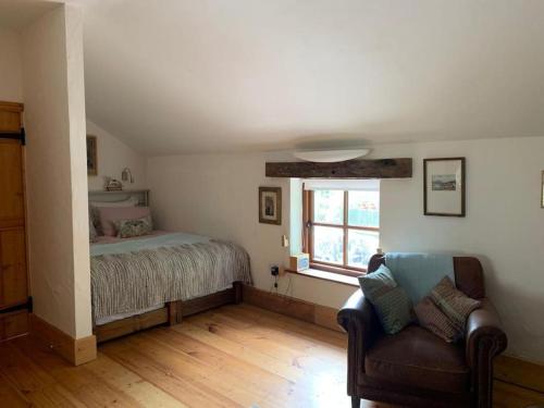 ein Schlafzimmer mit einem Bett, einem Sofa und einem Fenster in der Unterkunft The Nest at the Pink Cottage in Carmarthen