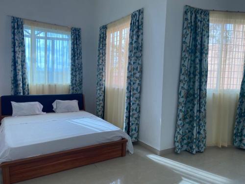 a bedroom with a bed with blue curtains at Lux Suites Mkomani Beachfront Apartment in Mombasa
