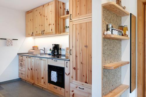 a kitchen with wooden cabinets and a stove at Tholerhof in San Genesio Atesino