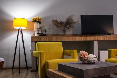 a living room with yellow chairs and a table and a television at R34 Boutique Guest House in Veliko Tŭrnovo