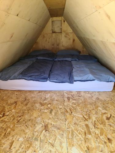 a bed in a tent with a wooden floor at Kopićland TENT in Marinci
