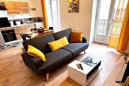 een woonkamer met een zwarte bank en gele kussens bij Bengale - T2 complétement rénové tout confort in Vichy