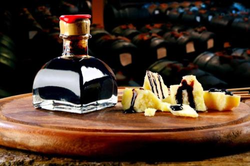 a bottle of syrup next to a plate of fruit at IZZ1 Apartments - Motor&Food Valley - Posto Auto Privato in Formigine