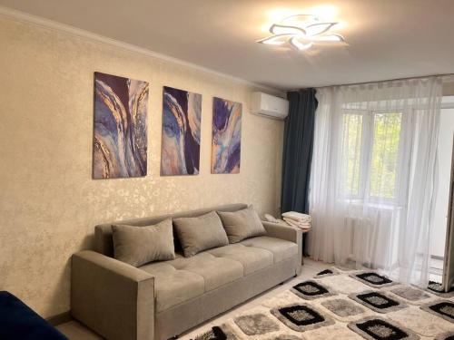 a living room with a couch and paintings on the wall at 2-х комнатная квартира в центре in Almaty