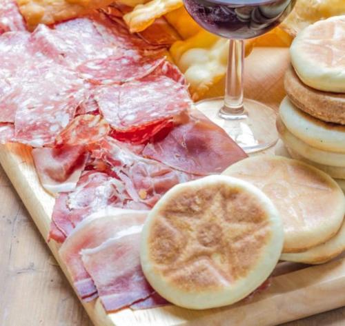 a plate of food with meat and a glass of wine at IZZ1 Apartments - Motor&Food Valley - Posto Auto Privato in Formigine