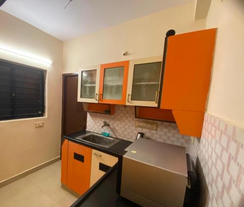 a small kitchen with orange cabinets and a sink at The Pearl 1Bhk / 2Bhk in Chennai