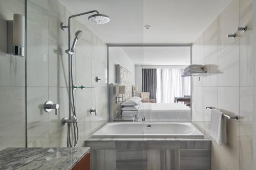 a bathroom with a tub and a shower with a mirror at Sheraton Melbourne Hotel in Melbourne