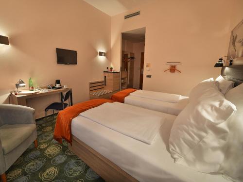 a hotel room with two beds and a desk at Ramada Airport Hotel Prague in Prague