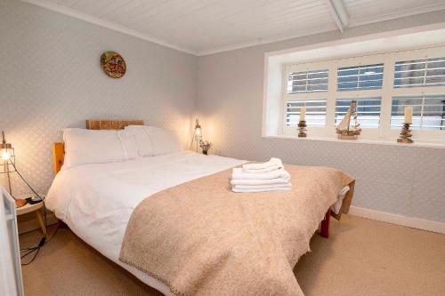 a bedroom with a large white bed and a window at Traditional Cottage with Private Hot Tub in the Heart of Donegal in Letterkenny