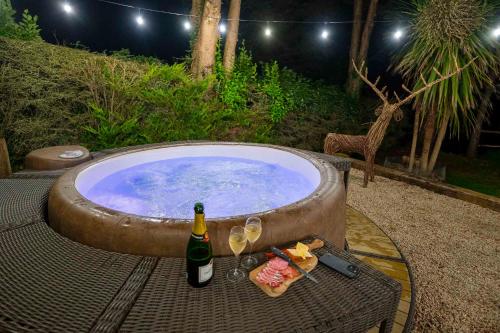 a bottle of wine and glasses next to a swimming pool at Traditional Cottage with Private Hot Tub in the Heart of Donegal in Letterkenny