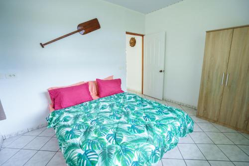 1 dormitorio con 1 cama grande con sábanas rosas y verdes en Noha Lodge, en Tohautu