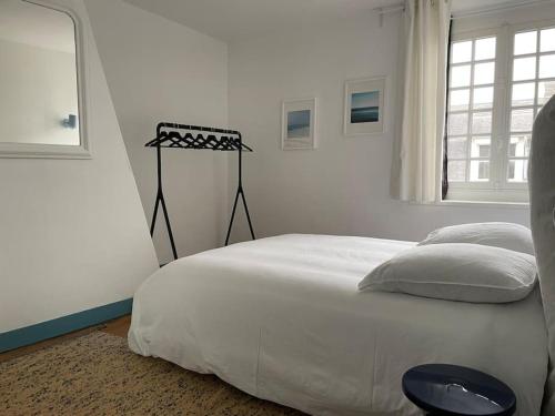 a white bedroom with a large bed and a window at En plein coeur du Crotoy, un pied à terre en Baie in Le Crotoy