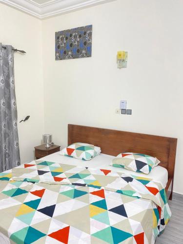 um quarto com uma cama com um edredão colorido em Chez rym 