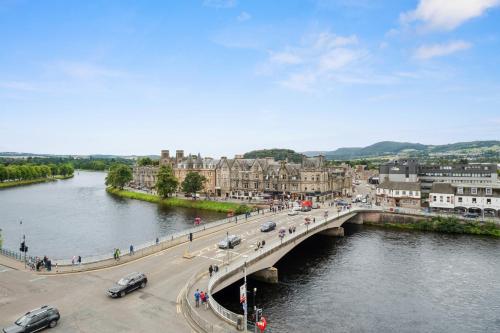 a bridge over a river in a city with cars at By the Bridge by Toppo in Inverness