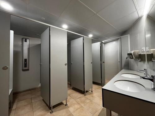 a public bathroom with three sinks and stalls at Cal Maco Alberg i centre de visitants in Igualada