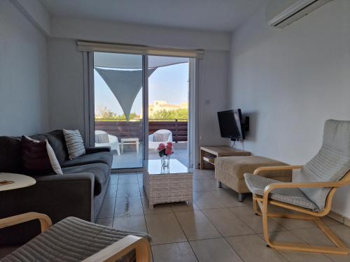 a living room with a couch and a tv at Kalifi Pool Apartment in Paralimni