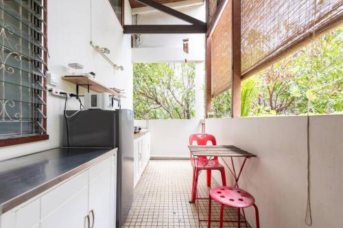 a kitchen with a table and a red stool at Bang Chak Homestay in Amphoe Phra Khanong
