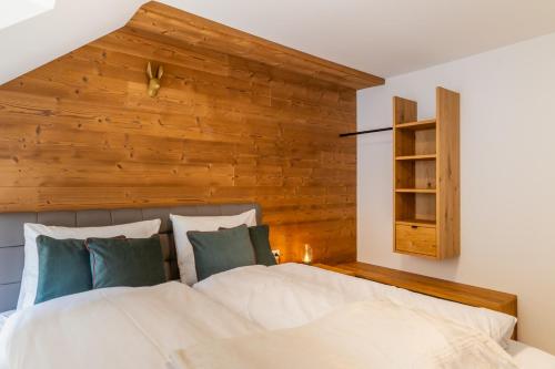 een slaapkamer met een groot bed en een houten muur bij Apartments Am Dorfplatzl in Hohentauern