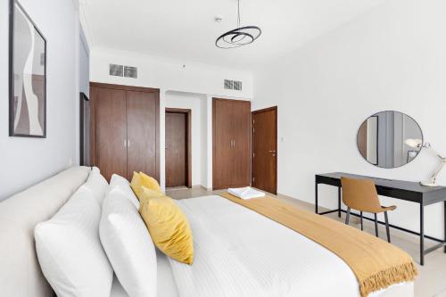 een slaapkamer met een groot wit bed met gele kussens bij Silkhaus Luxurious Pool & Gym 1BDR Art Residence in Dubai